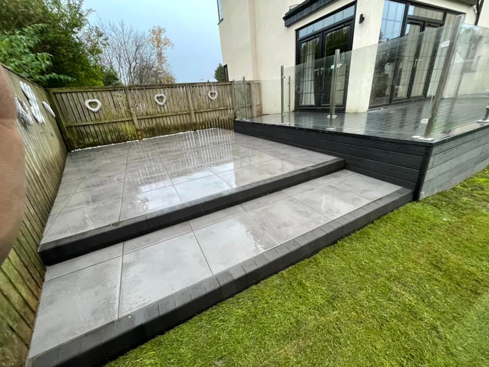 Indie paving & R M Joinery collaboration with this garden makeover installing a large composite deck with glass balustrade, porcelain patio and steps