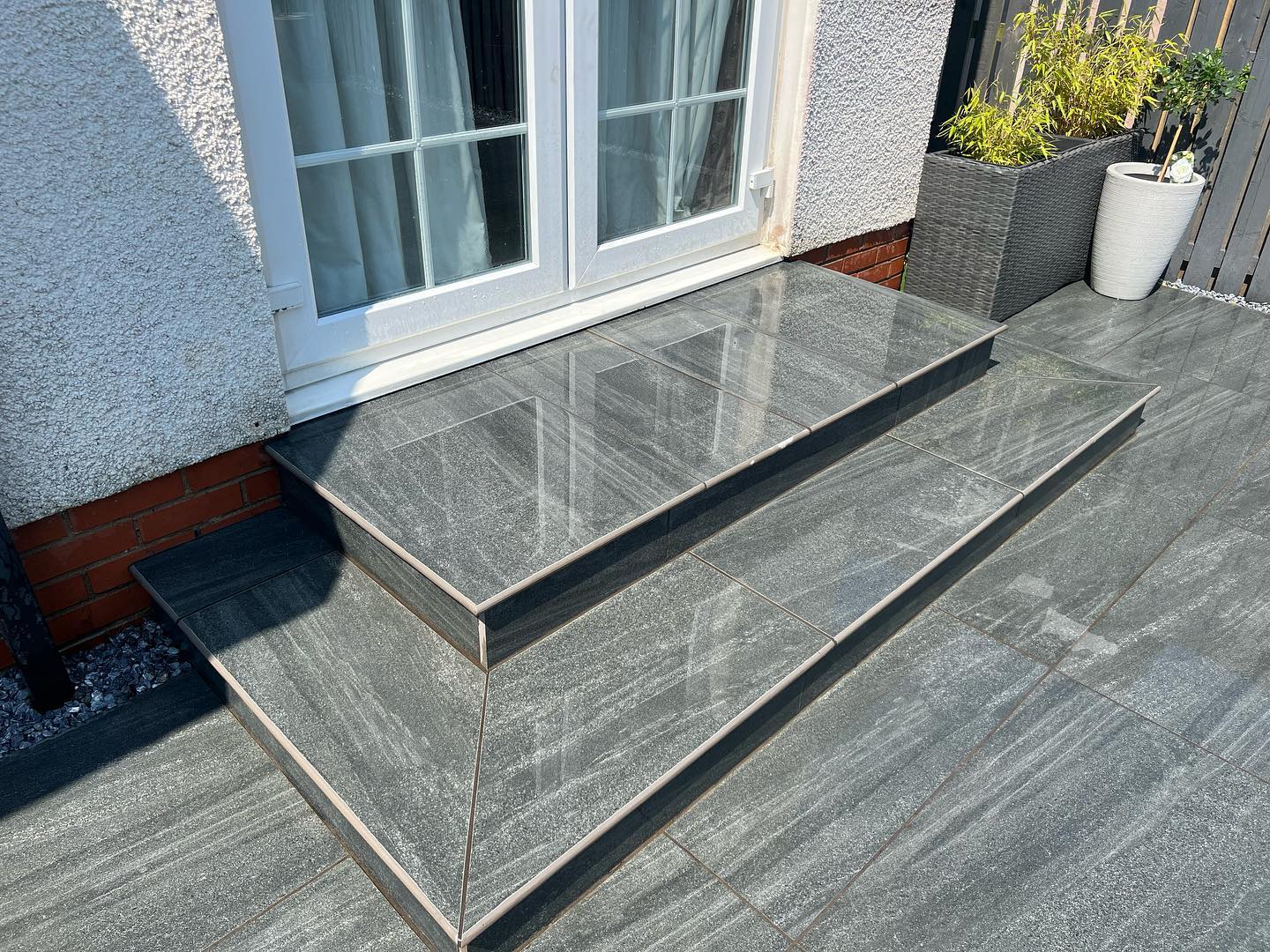 Smokey jewel porcelain patio installed with curving path , granite set border and new steps with a bullnose finish
