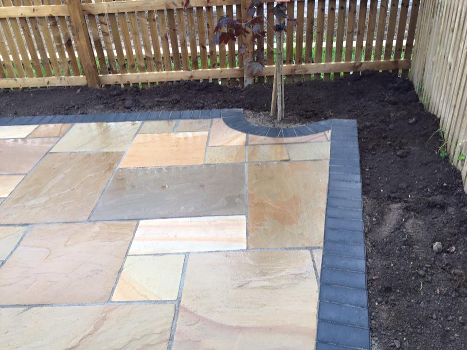 Buff multi Indian sandstone patio with charcoal block edging