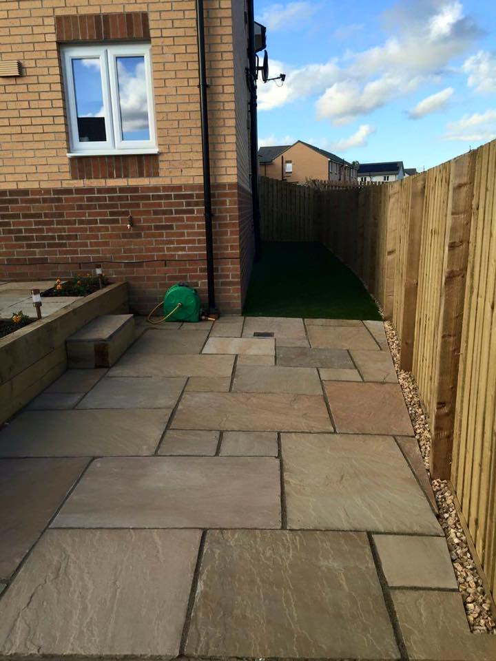 Total garden transformation split into 3 different levels with timber sleeper walls , Indian sandstone patios and paths , artificial grass , play bark and new fence around the perimeter.